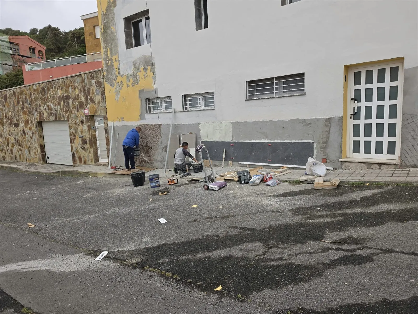 Albañiles colocando plaqueta en el zócalo de una fachada en Las Palmas de Gran Canaria