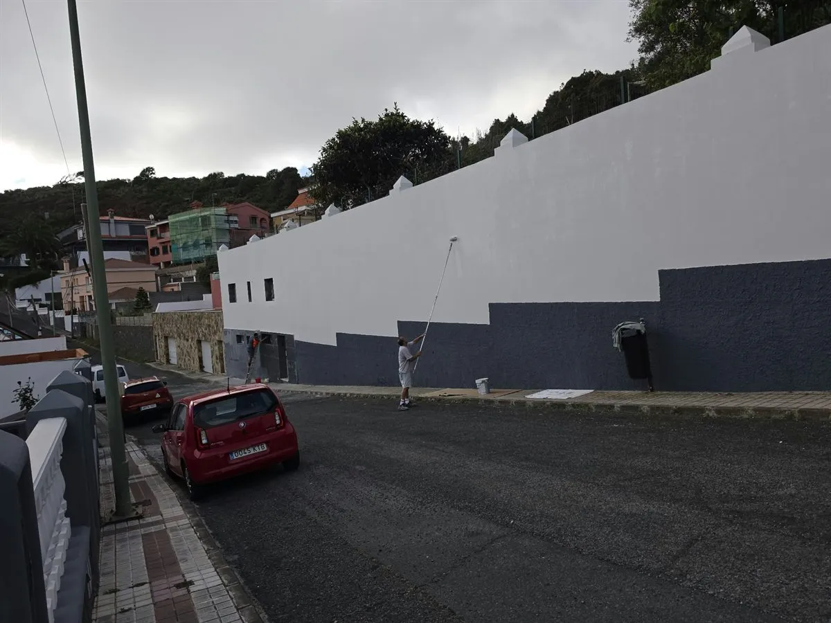 Operario pintando un muro con rodillo de pértiga durante la rehabilitación de una fachada en Las Palmas de Gran Canaria